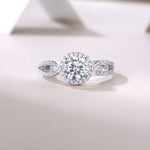 CARISSIE round moissanite halo ring, lifestyle shot on textured surface with soft lighting enhancing the gemstone brilliance
