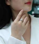 CARISSIE round moissanite halo ring on model, close-up of hand touching chin highlighting silver-tone metal and sparkle