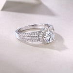 CARISSIE round moissanite halo ring on textured surface, angled perspective showing polished silver metal