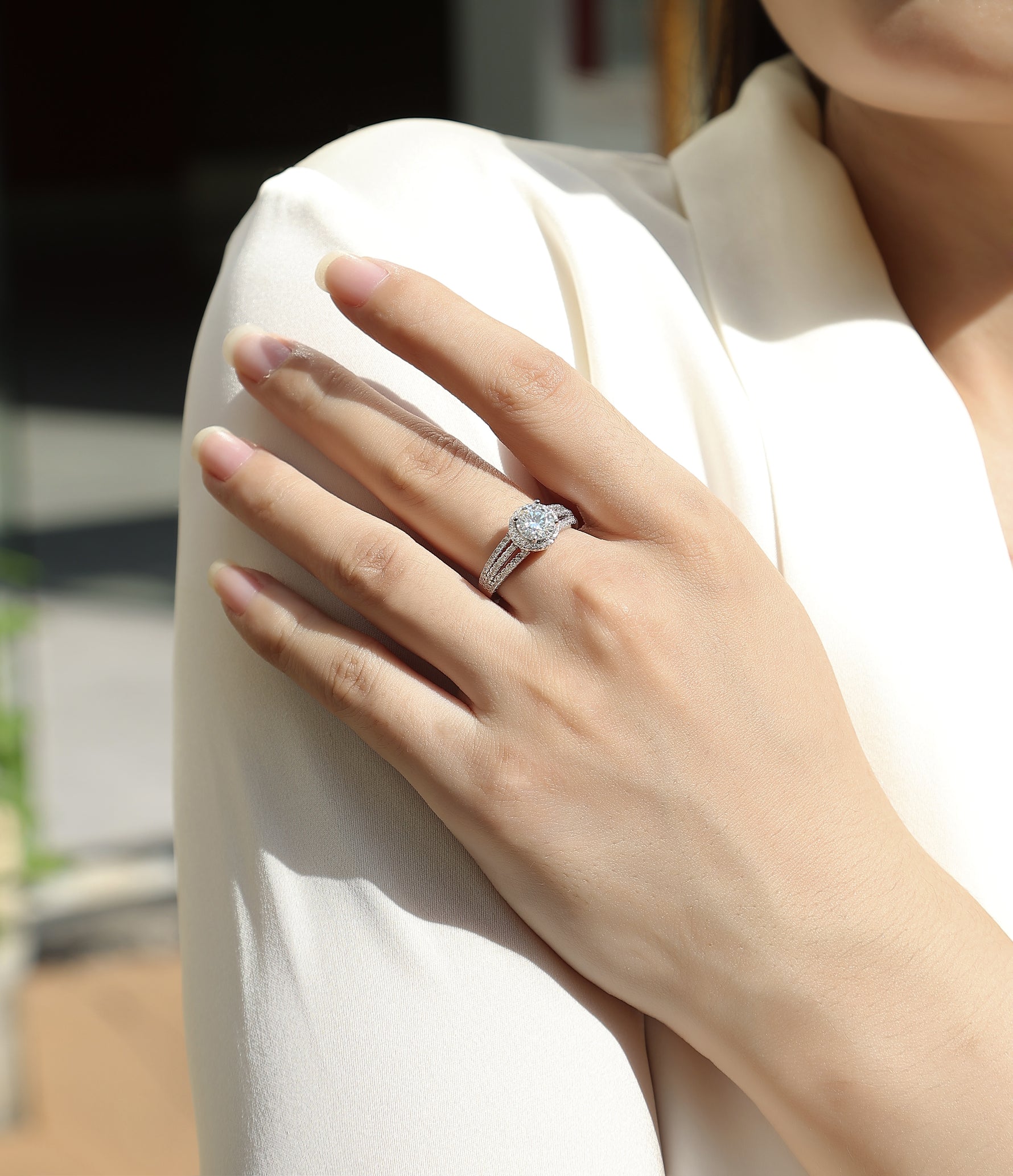 CARISSIE round moissanite halo ring on model, resting on white sleeve showing split shank band