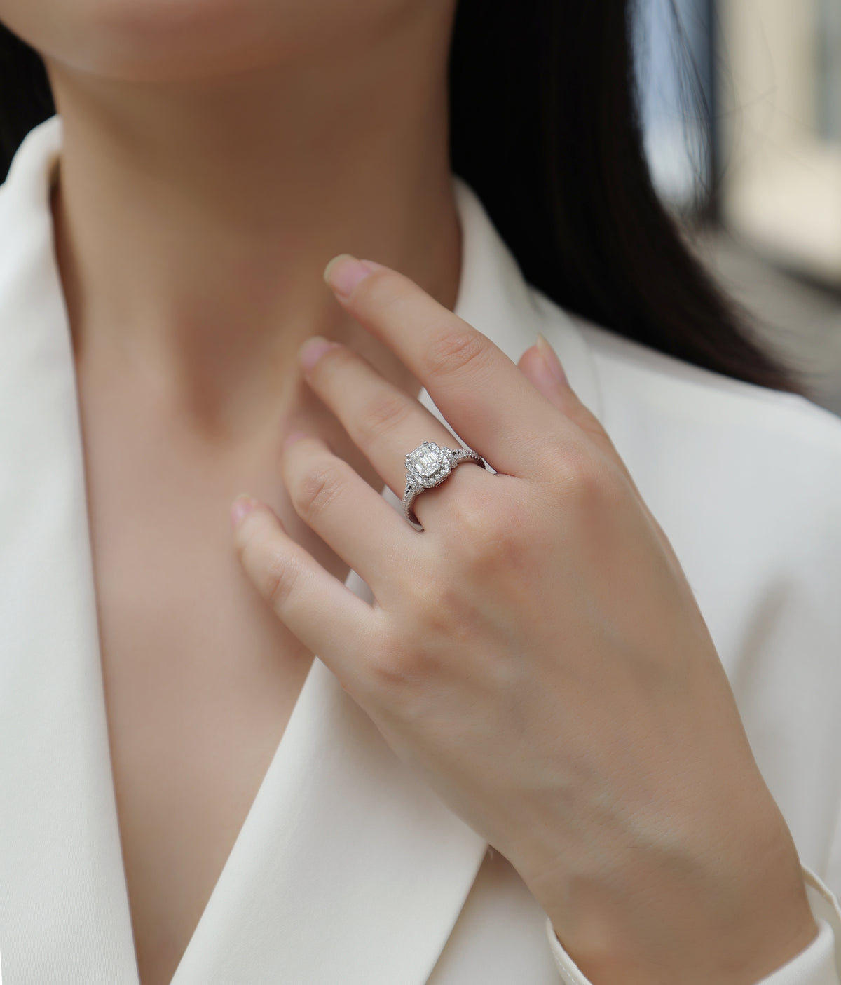 CARISSIE emerald cut moissanite halo ring on model, showing elegant wear against white blazer