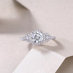 CARISSIE round moissanite halo ring resting on textured paper, close-up shot emphasizing the brilliance of the central gemstone