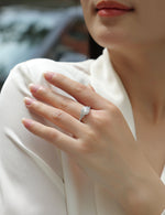 CARISSIE round moissanite engagement ring worn on hand, highlighting the sparkling halo and geometric shoulder details