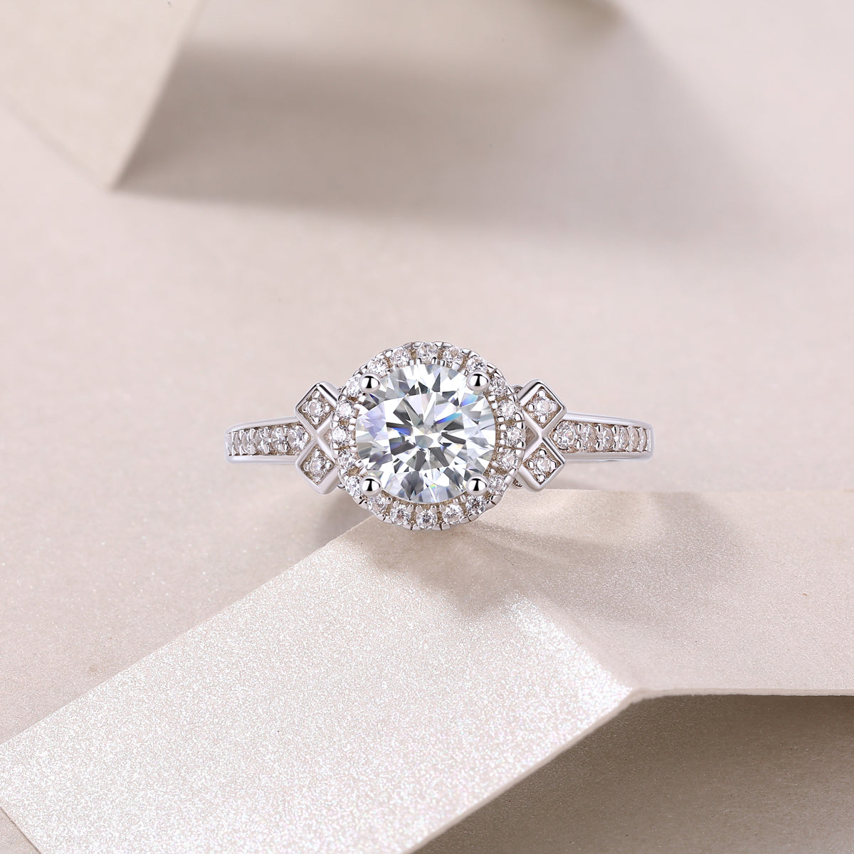 CARISSIE round moissanite ring resting on textured paper, capturing the sparkle of the 1ct center stone and surrounding halo