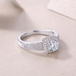 CARISSIE cushion moissanite halo wedding band three-quarter angle on fabric, showcasing the transition from paved shoulders to plain band