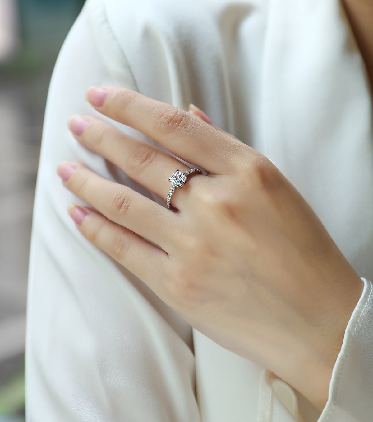 CARISSIE round moissanite solitaire ring worn on hand, angled view highlighting the elevated center stone and accent diamonds
