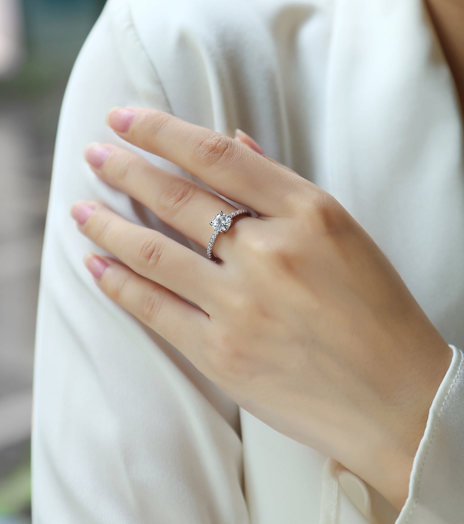 CARISSIE round moissanite solitaire ring worn on hand, angled view highlighting the elevated center stone and accent diamonds