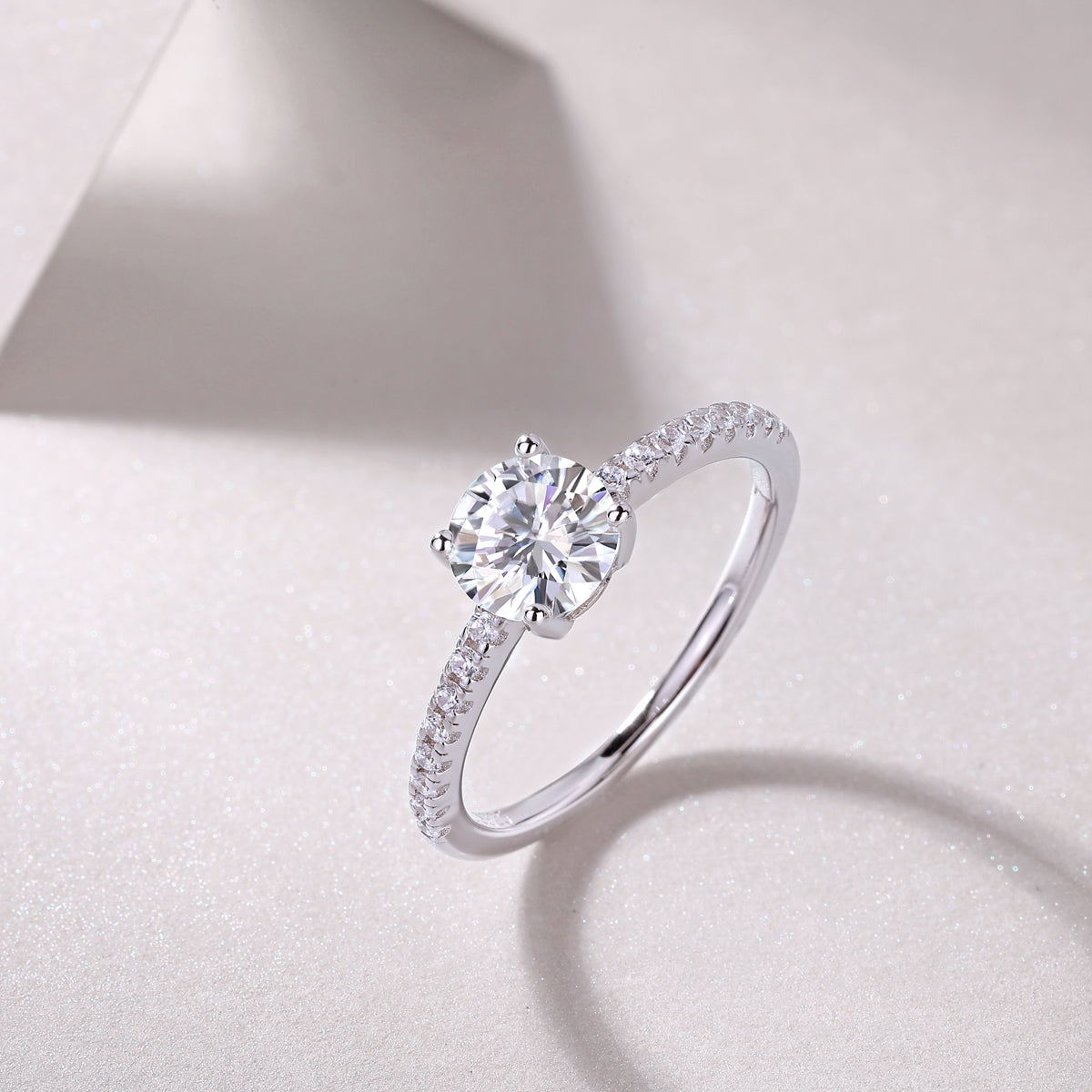 CARISSIE round moissanite solitaire ring artistic angle, capturing light reflection on the faceted stone and polished white metal