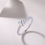 CARISSIE round moissanite solitaire ring artistic angle, capturing light reflection on the faceted stone and polished white metal