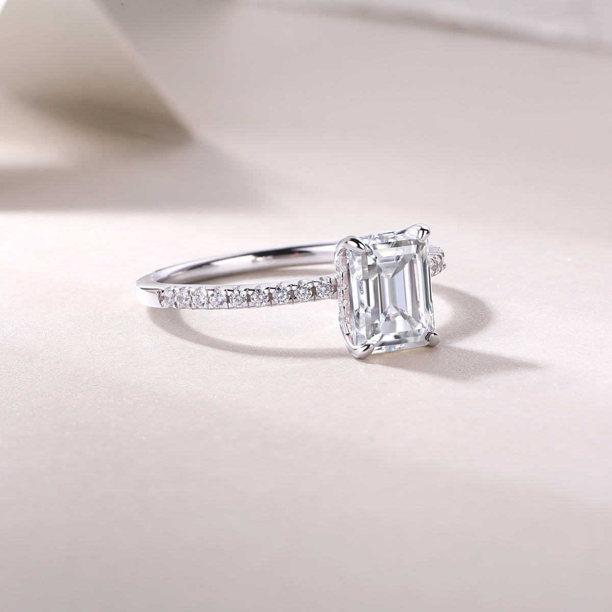 CARISSIE solitaire ring angled product shot on textured surface, catching light on the clear rectangular gemstone