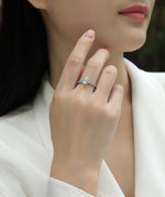 CARISSIE pear moissanite solitaire ring on model, hand near face showing silver-tone metal and pavé band