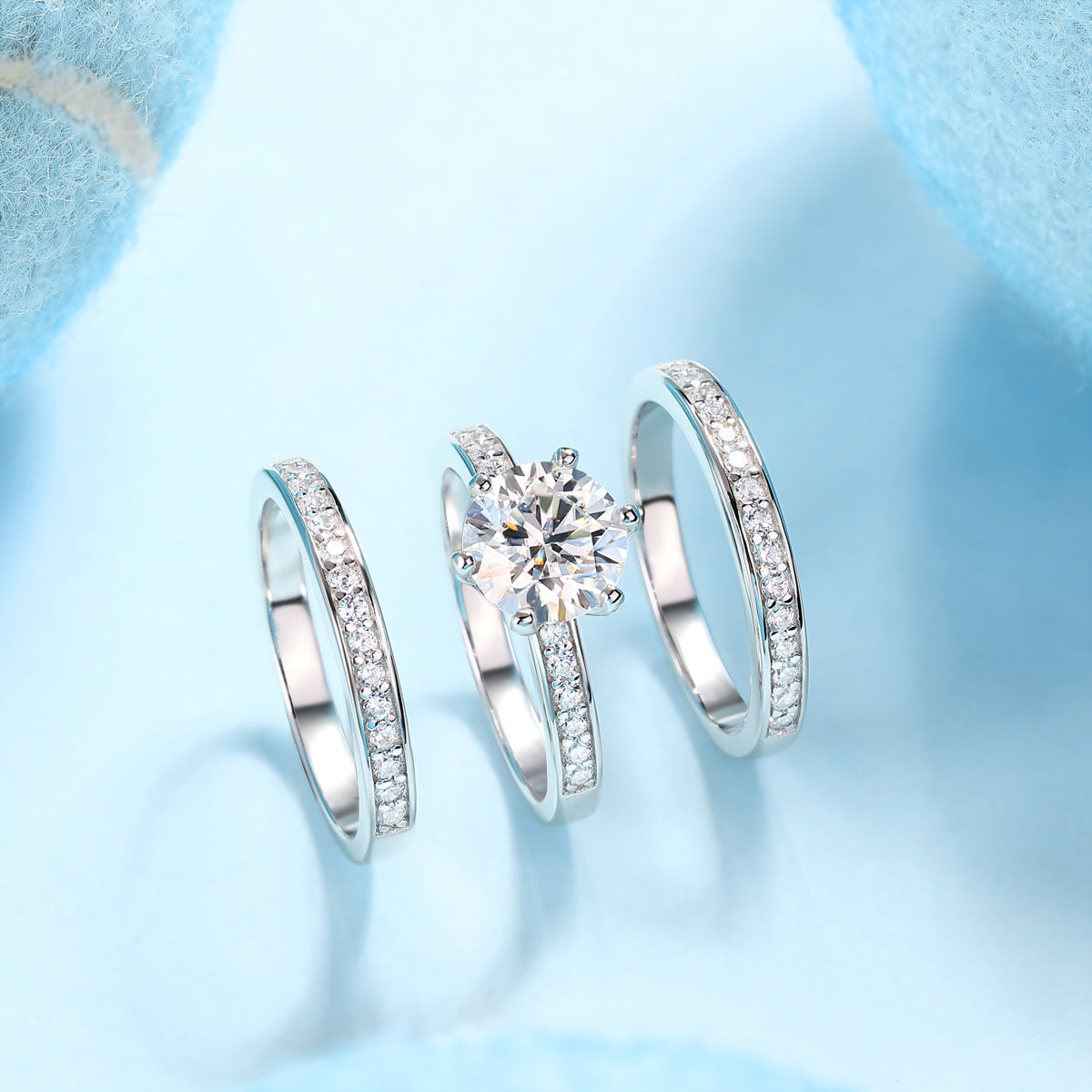 CARISSIE round moissanite solitaire ring set, arranged layout on blue surface showing individual band components