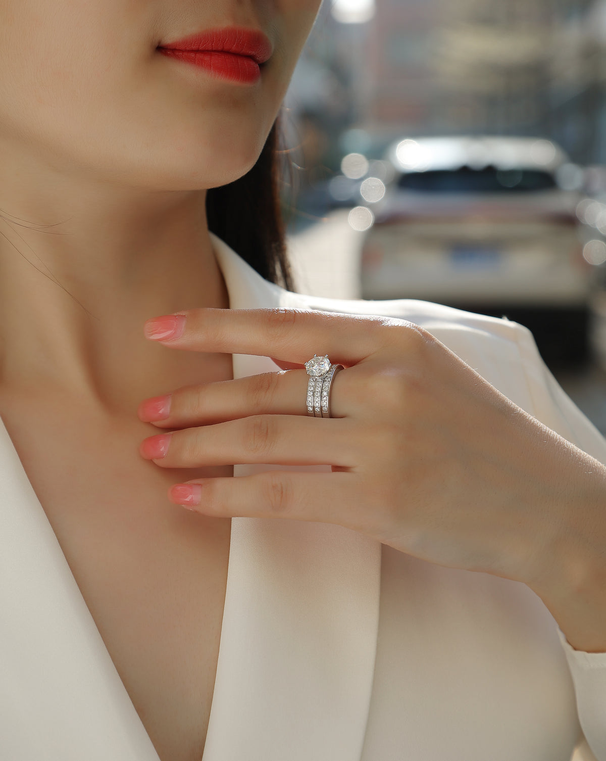 CARISSIE round moissanite solitaire ring set, lifestyle view on model with city background showing three-band design