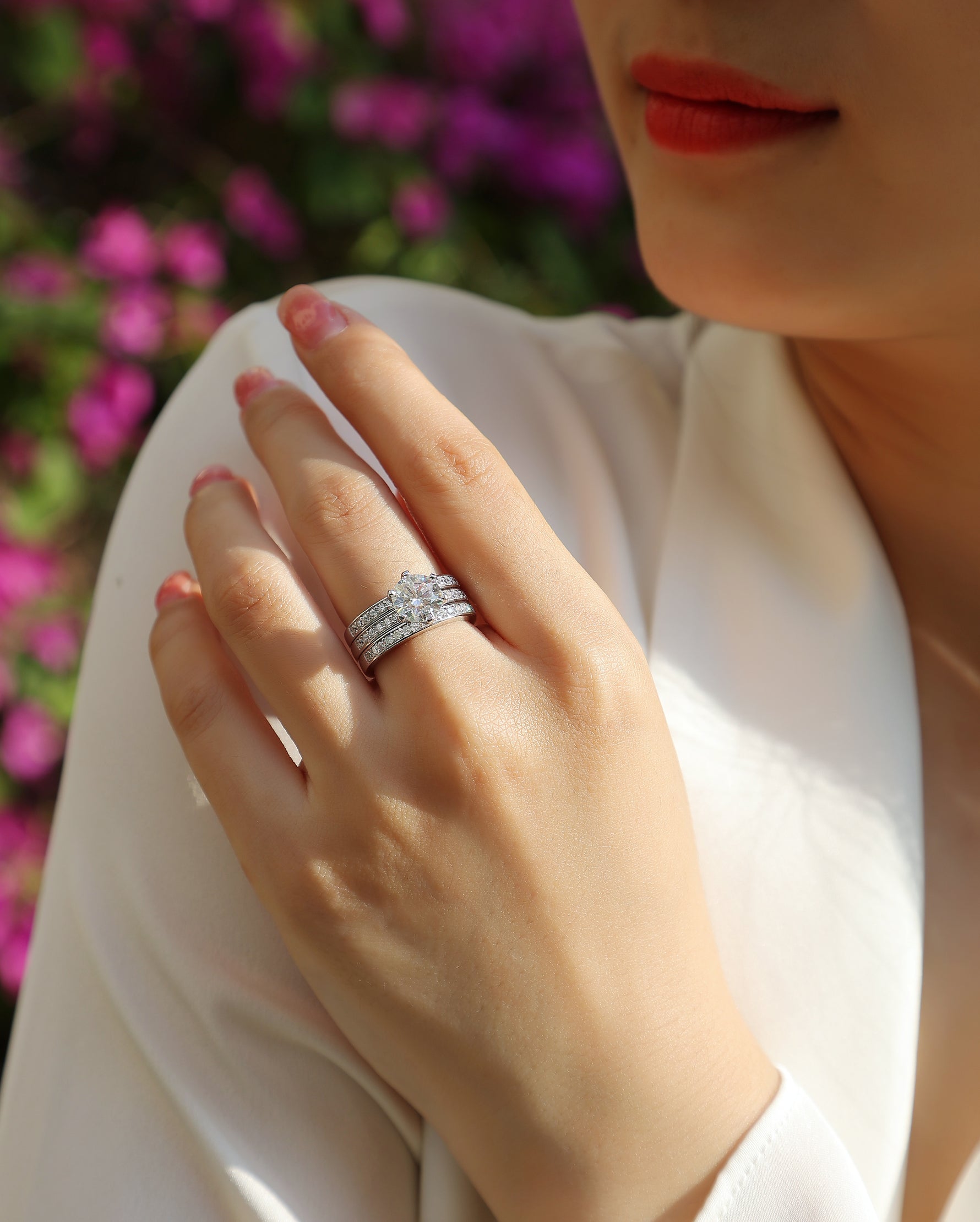 CARISSIE round moissanite solitaire ring set, close-up on hand against floral backdrop highlighting stone sparkle