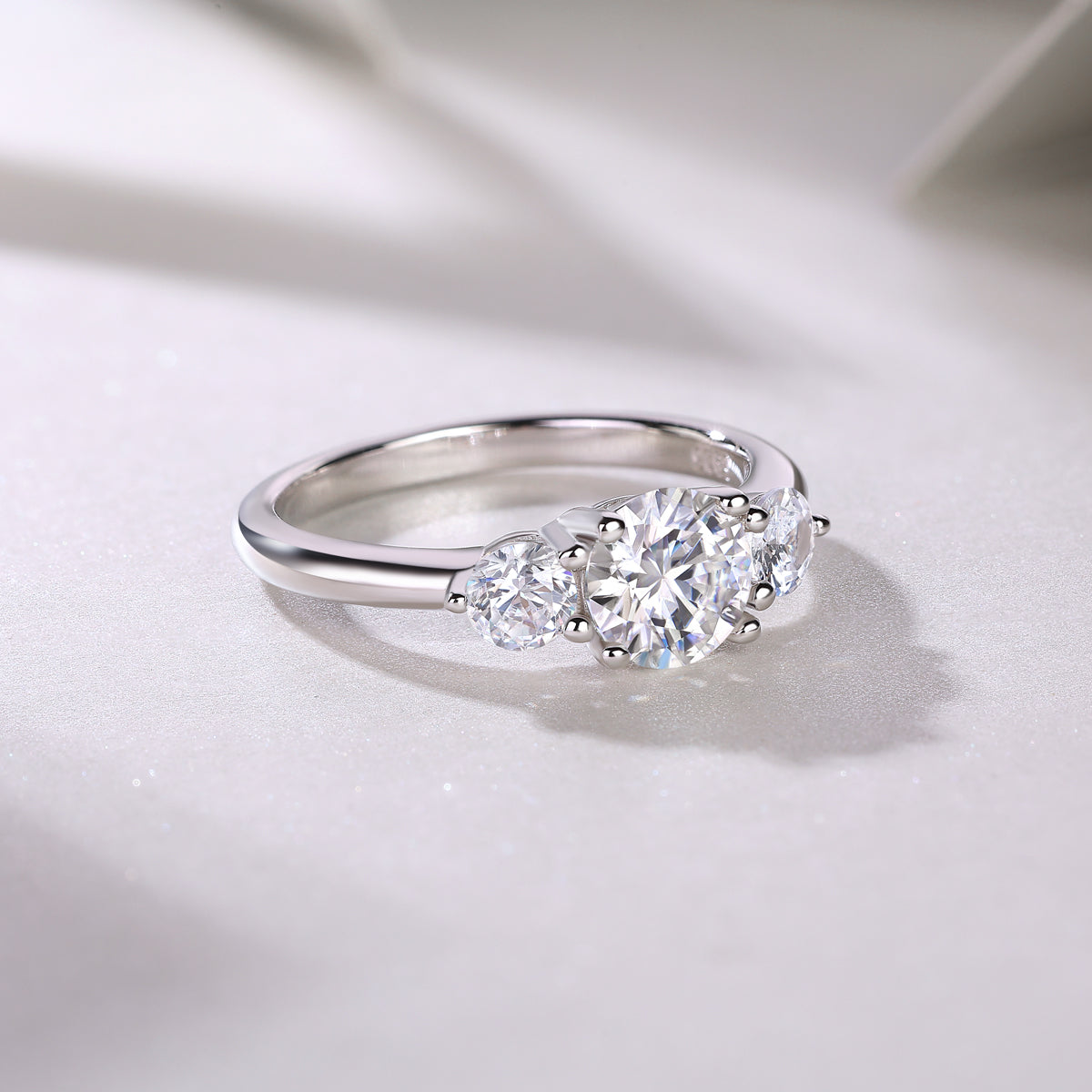 CARISSIE round moissanite solitaire ring, diagonal angle showcasing the curvature of the band and brilliance of the gems