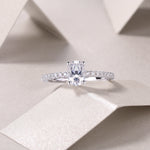 CARISSIE oval moissanite solitaire ring lifestyle shot on textured paper surface, capturing fire and brilliance in soft lighting