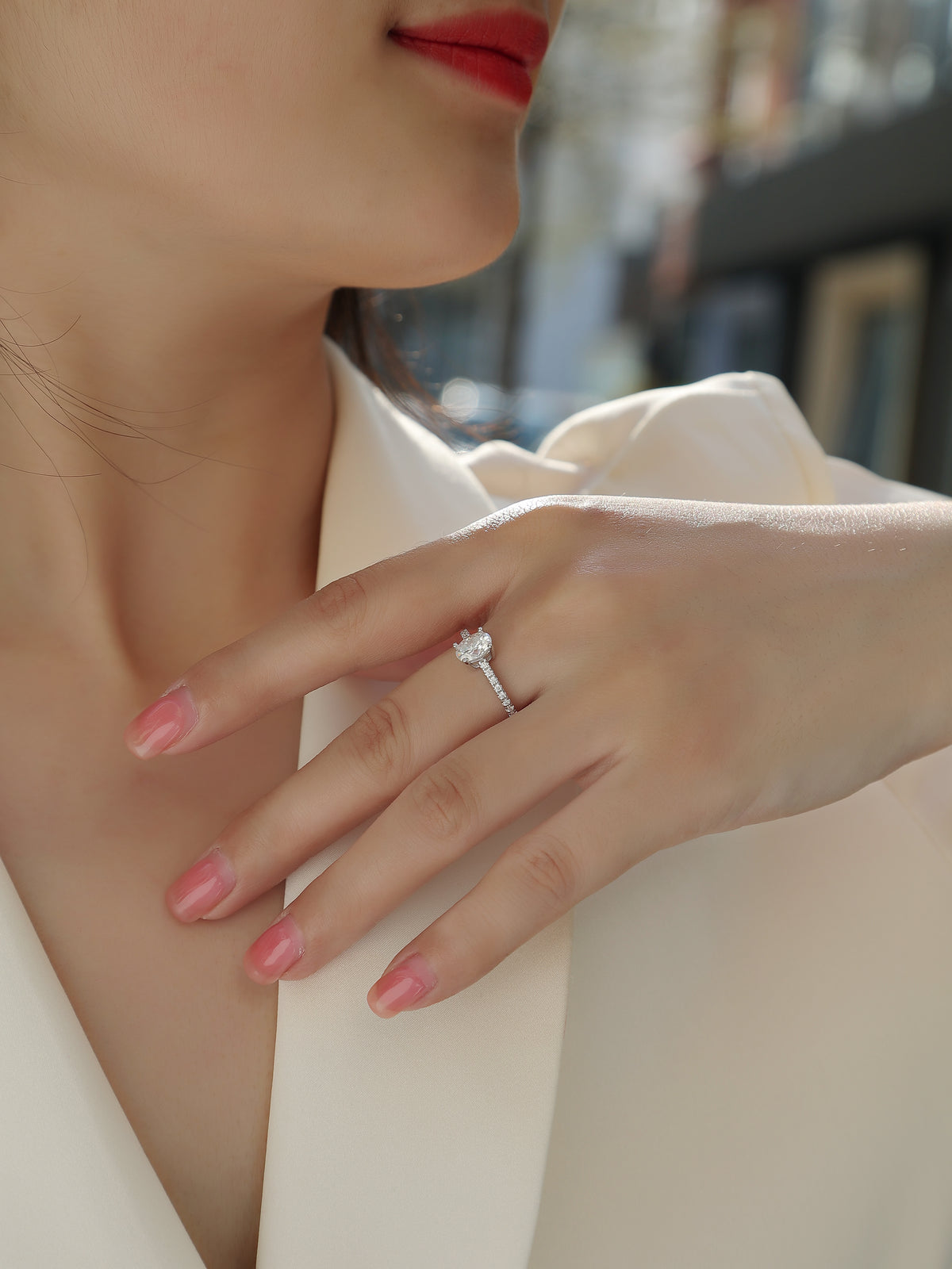 CARISSIE oval moissanite solitaire ring on model hand, resting against white fabric with natural light highlighting the stone