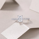 CARISSIE moissanite ring styled on textured paper, emphasizing the brilliance of the 5x7mm center stone