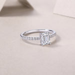 CARISSIE emerald cut solitaire ring diagonal angle, capturing light reflection on silver-tone metal and gems