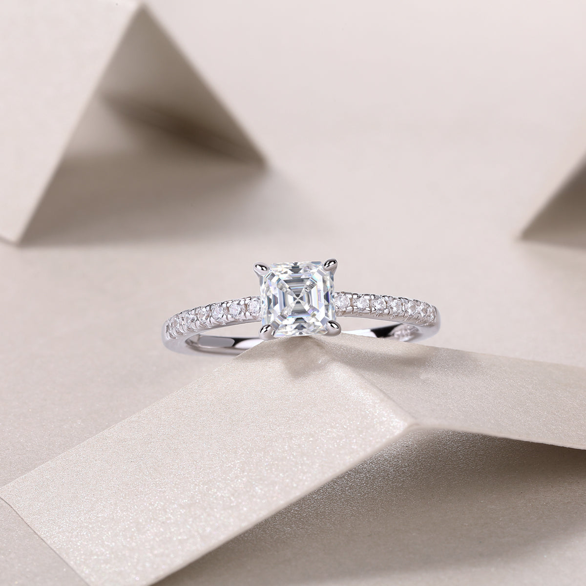 CARISSIE Asscher solitaire engagement ring lifestyle shot, featuring the sparkling center stone and delicate band on folded paper