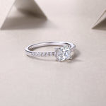 CARISSIE Asscher solitaire engagement ring resting on textured surface, capturing light reflection on the square cut and silver band