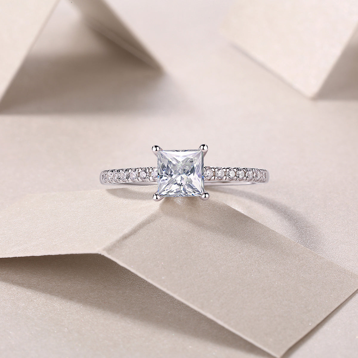 CARISSIE solitaire engagement ring top-down view on paper background, featuring brilliant square stone and delicate band