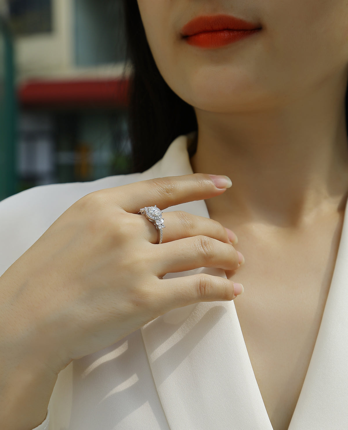 CARISSIE round moissanite halo engagement ring worn on finger, showing pavé band sparkle against soft skin tone