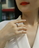 CARISSIE round moissanite halo engagement ring worn on finger, showing pavé band sparkle against soft skin tone