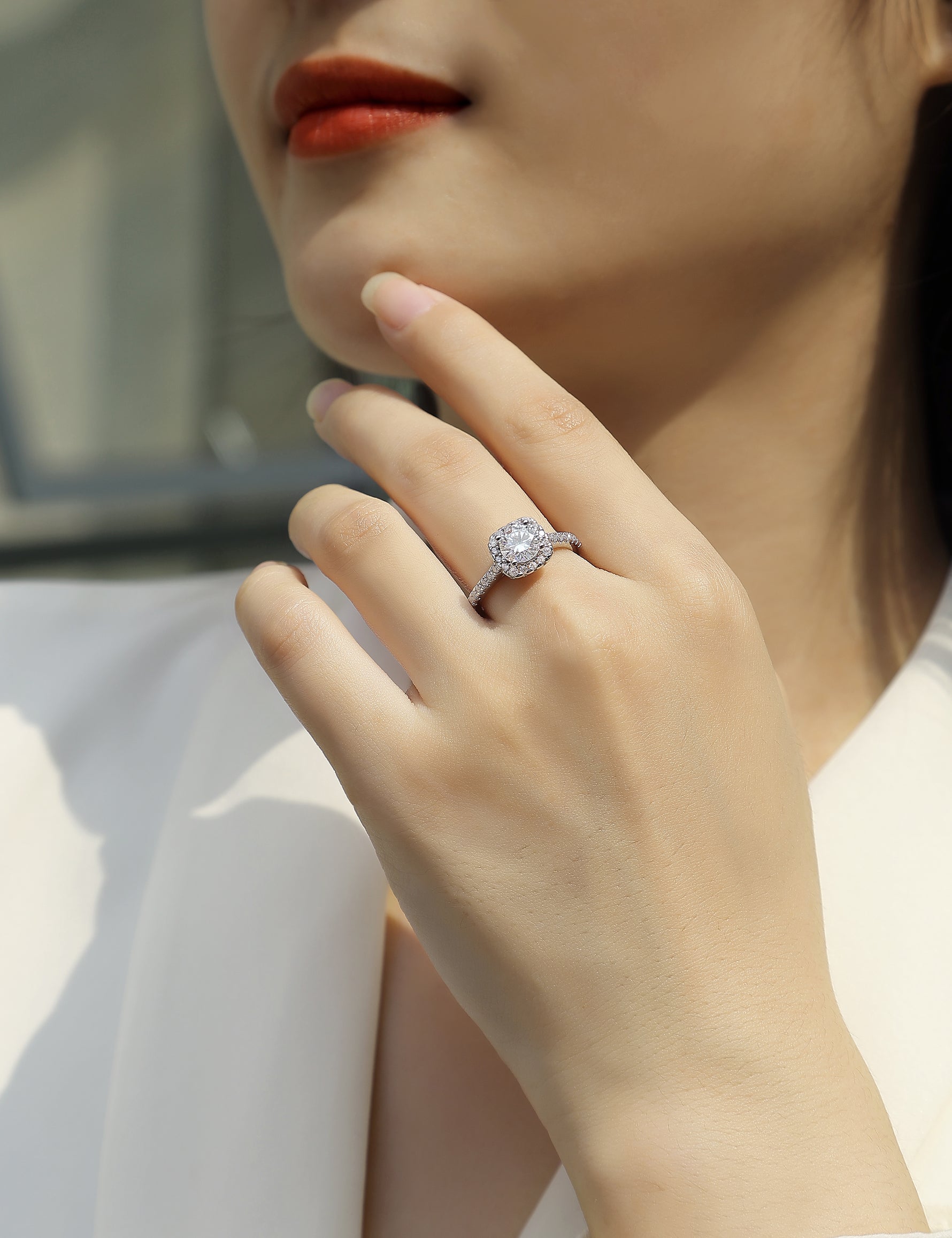 CARISSIE round moissanite halo ring on model, showing elegant profile and pavé band against white blouse