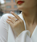 CARISSIE round moissanite engagement ring lifestyle shot, hand resting on shoulder with blurred background