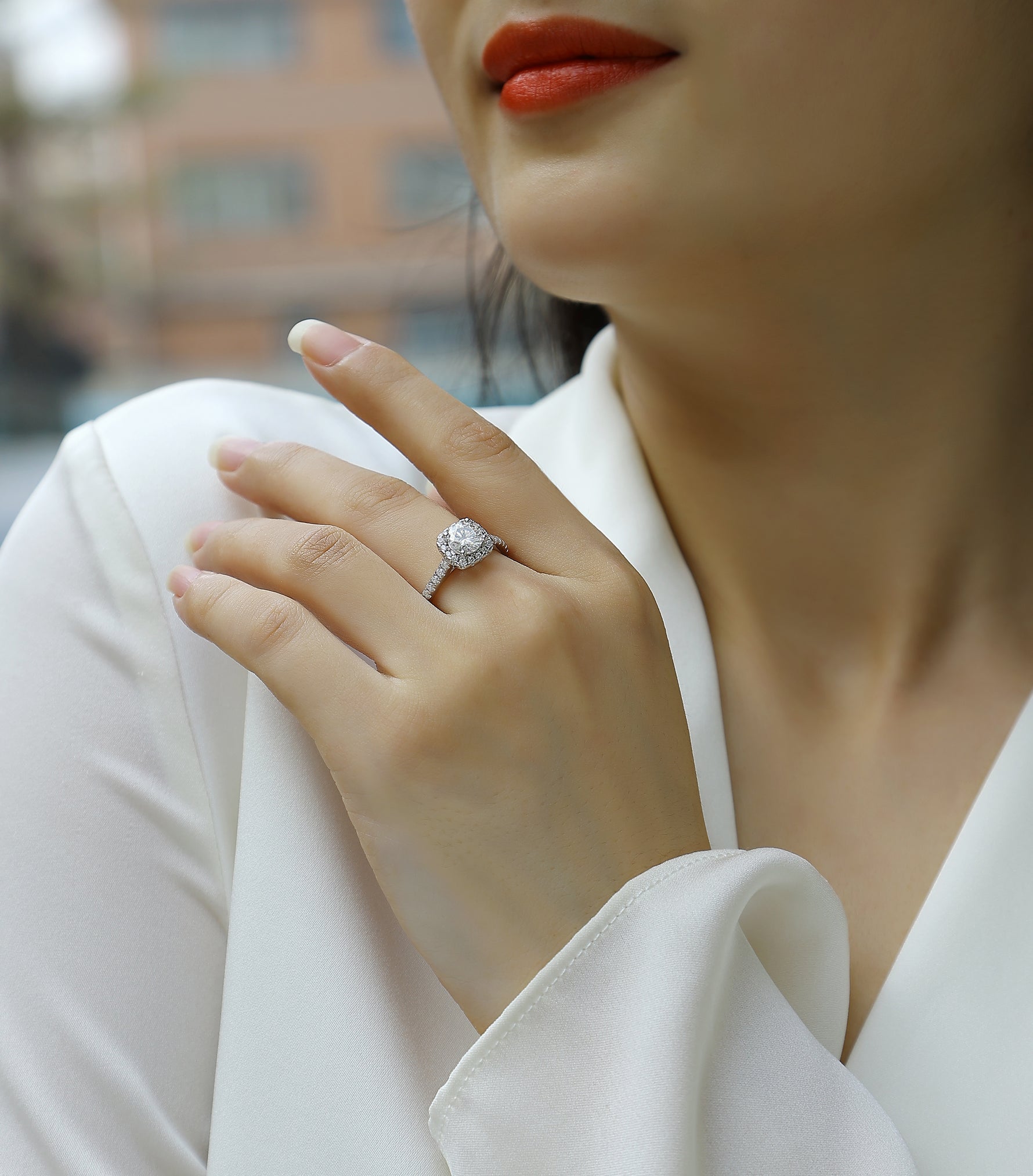CARISSIE round moissanite engagement ring lifestyle shot, hand resting on shoulder with blurred background