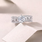 CARISSIE round moissanite solitaire ring studio close-up, featuring twisting pavé bands and center stone on fabric