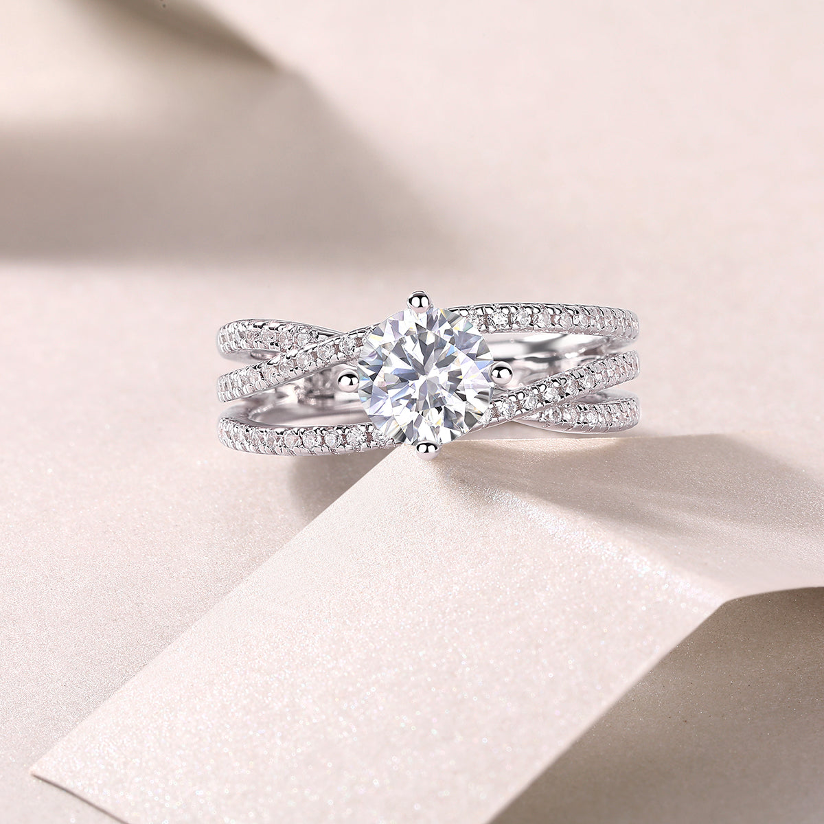 CARISSIE round moissanite solitaire ring studio close-up, featuring twisting pavé bands and center stone on fabric