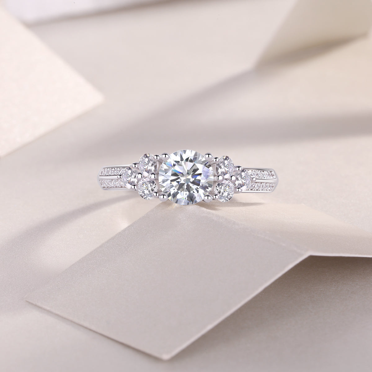 CARISSIE round moissanite solitaire ring, lifestyle shot resting on textured paper with soft lighting accentuating sparkle