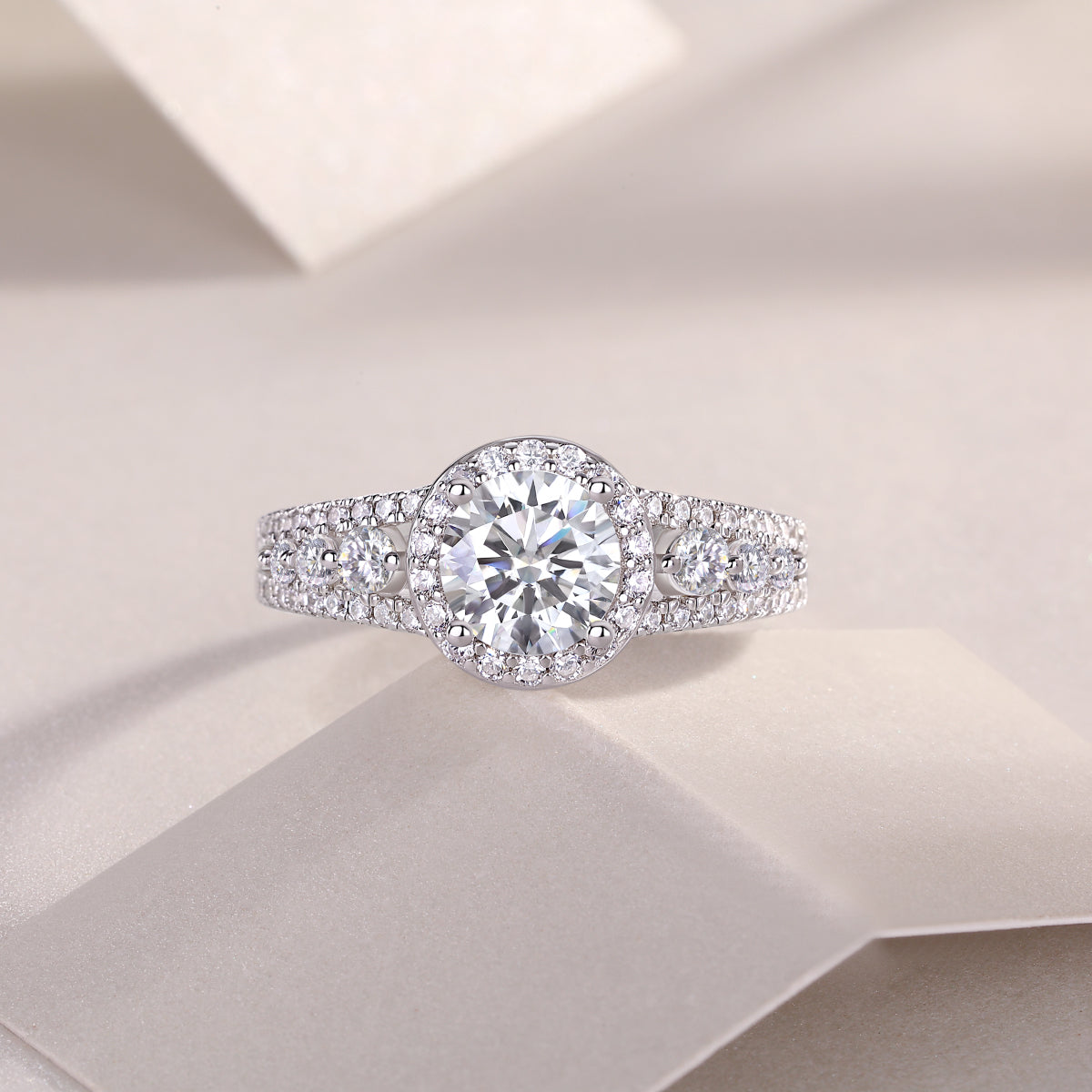 CARISSIE round moissanite solitaire ring, lifestyle shot on white textured surface emphasizing sparkle and intricate details