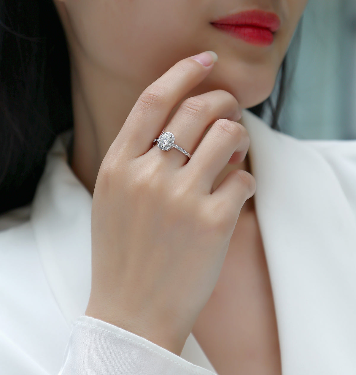 CARISSIE oval moissanite halo engagement ring worn on finger, close-up view of setting against skin