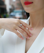 CARISSIE oval moissanite halo engagement ring on model hand with white blazer, showing elegant fit and sparkle