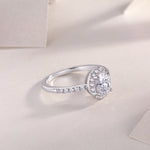 CARISSIE oval moissanite halo engagement ring three-quarter angle on display stand showing curved band design