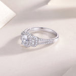 CARISSIE oval moissanite halo ring resting on textured surface, showcasing polished inner band and side stones