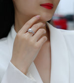 CARISSIE round moissanite halo engagement ring, on model close-up with hand near face showcasing sparkle against skin
