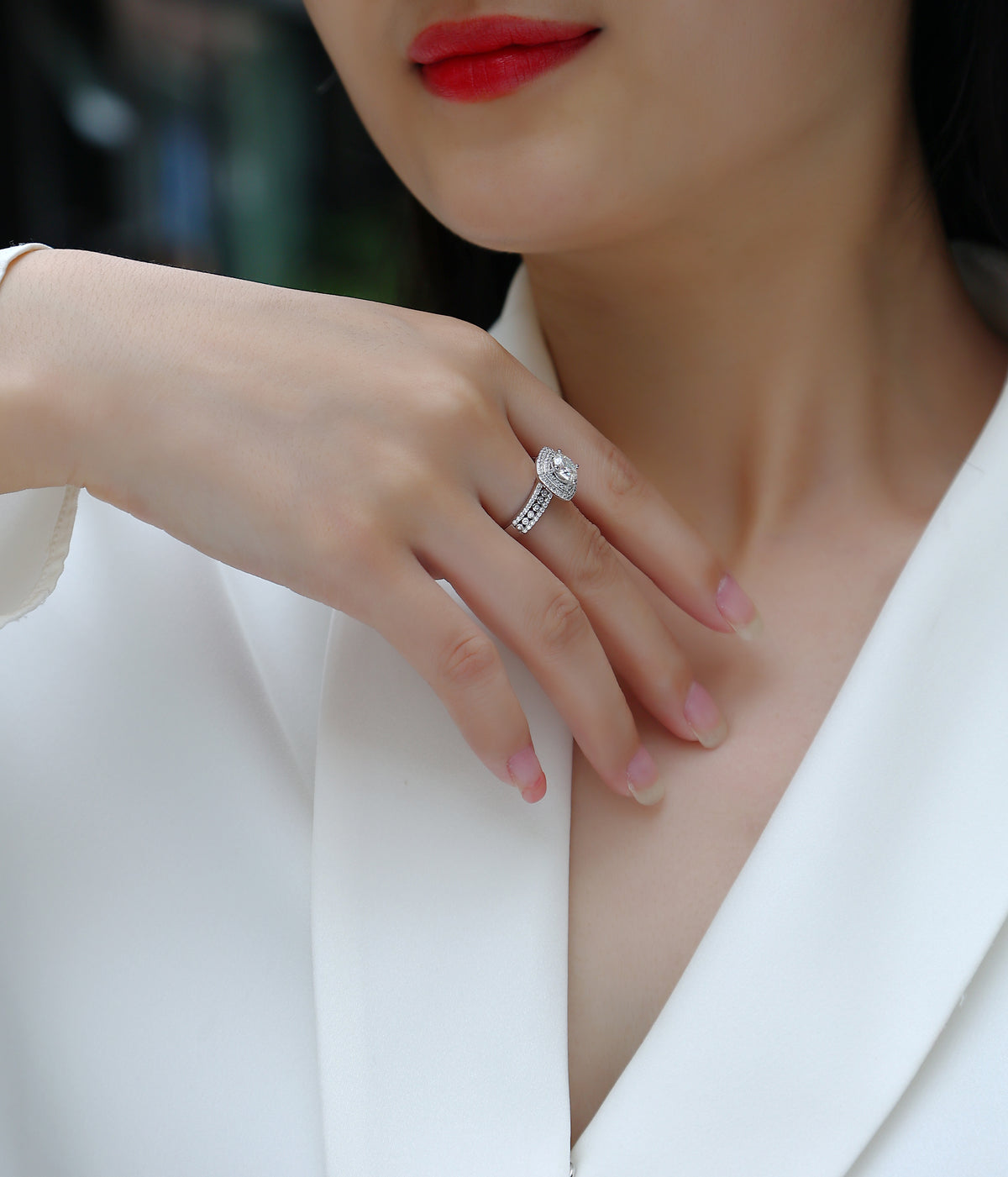 CARISSIE round moissanite halo engagement ring, lifestyle shot on hand resting on white blazer lapel