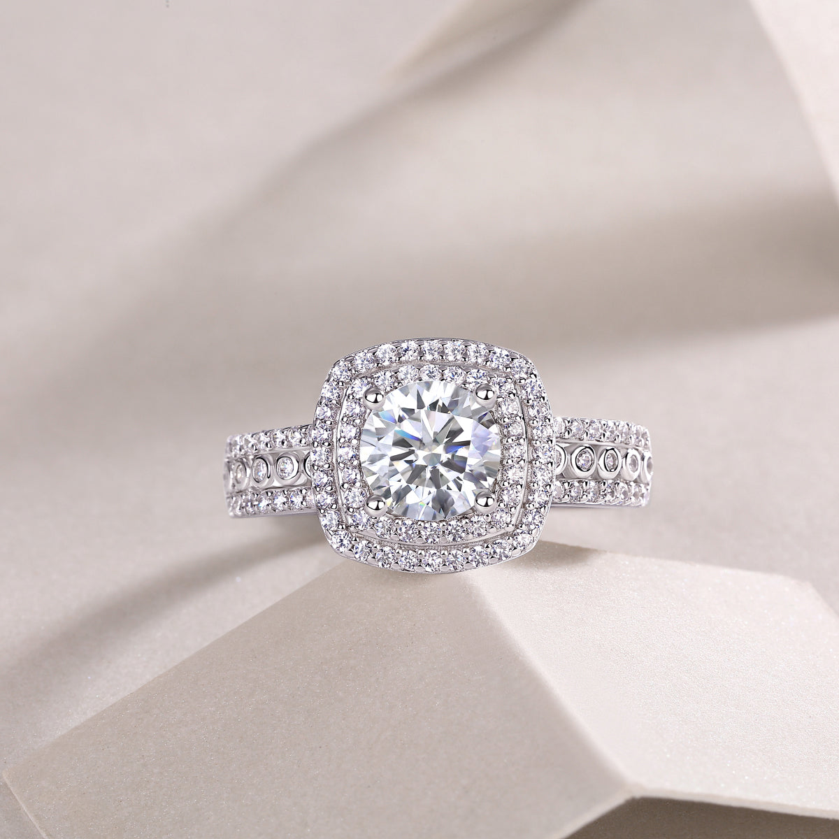 CARISSIE round moissanite halo engagement ring, flat lay perspective emphasizing geometric contrast of halos on soft background