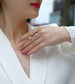 CARISSIE oval moissanite engagement ring on model, showing split shank band and center stone against white blazer
