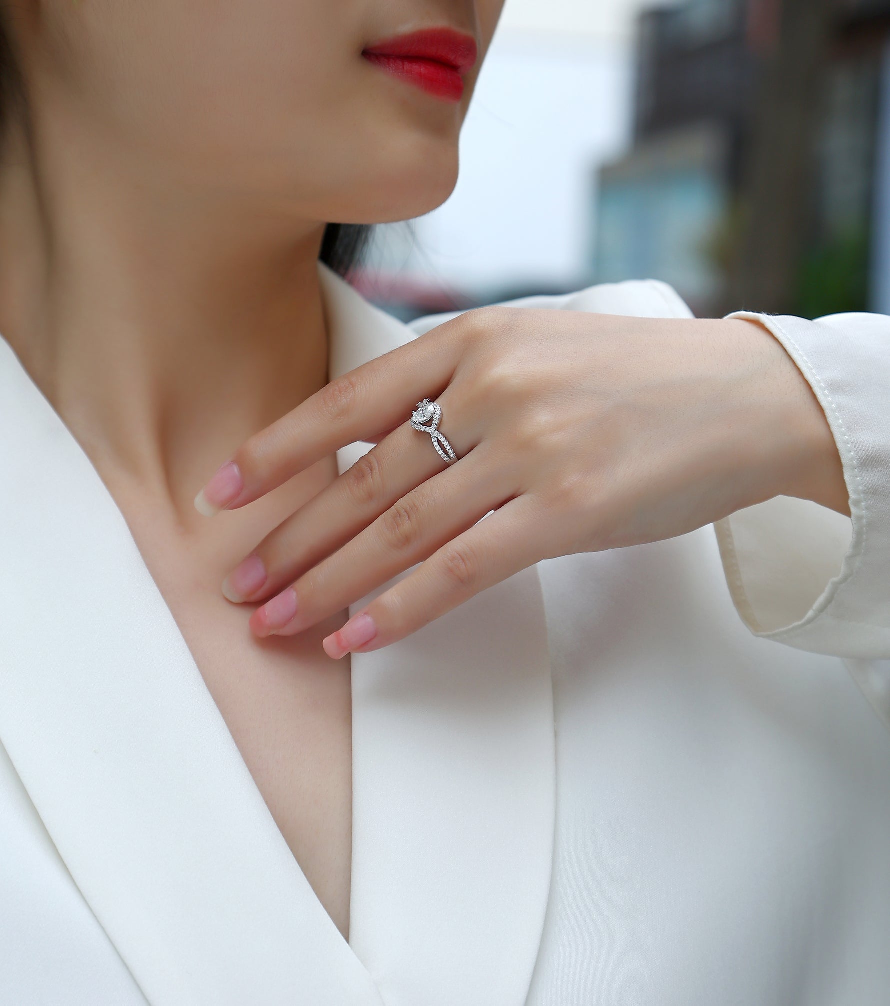 CARISSIE oval moissanite engagement ring on model, showing split shank band and center stone against white blazer