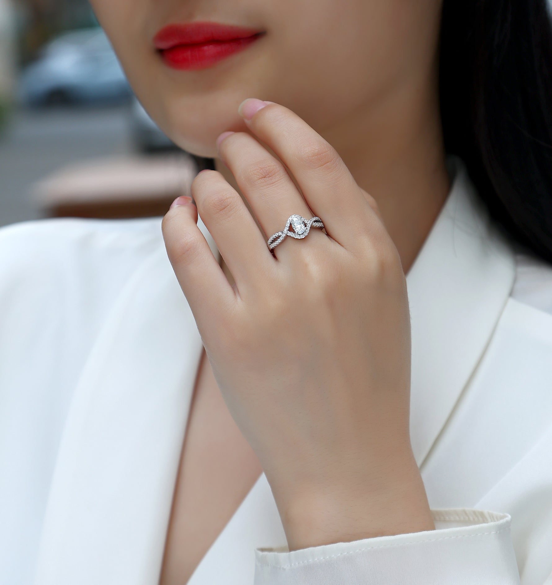 CARISSIE oval moissanite solitaire ring worn by woman, highlighting the crossover pavé design near her face
