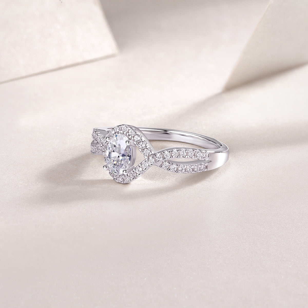 CARISSIE oval moissanite ring lifestyle shot, resting on textured cream surface with soft lighting and shadows