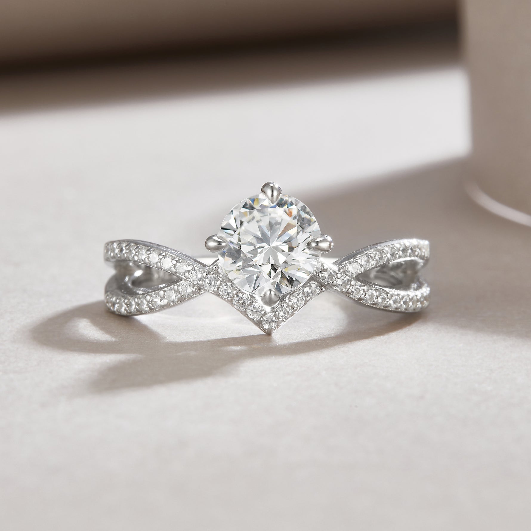 CARISSIE round moissanite solitaire ring, lifestyle shot on a soft surface capturing light reflection on the silver-tone metal
