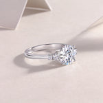 CARISSIE round moissanite engagement ring, angled lifestyle perspective showing the polished silver finish and side stone details