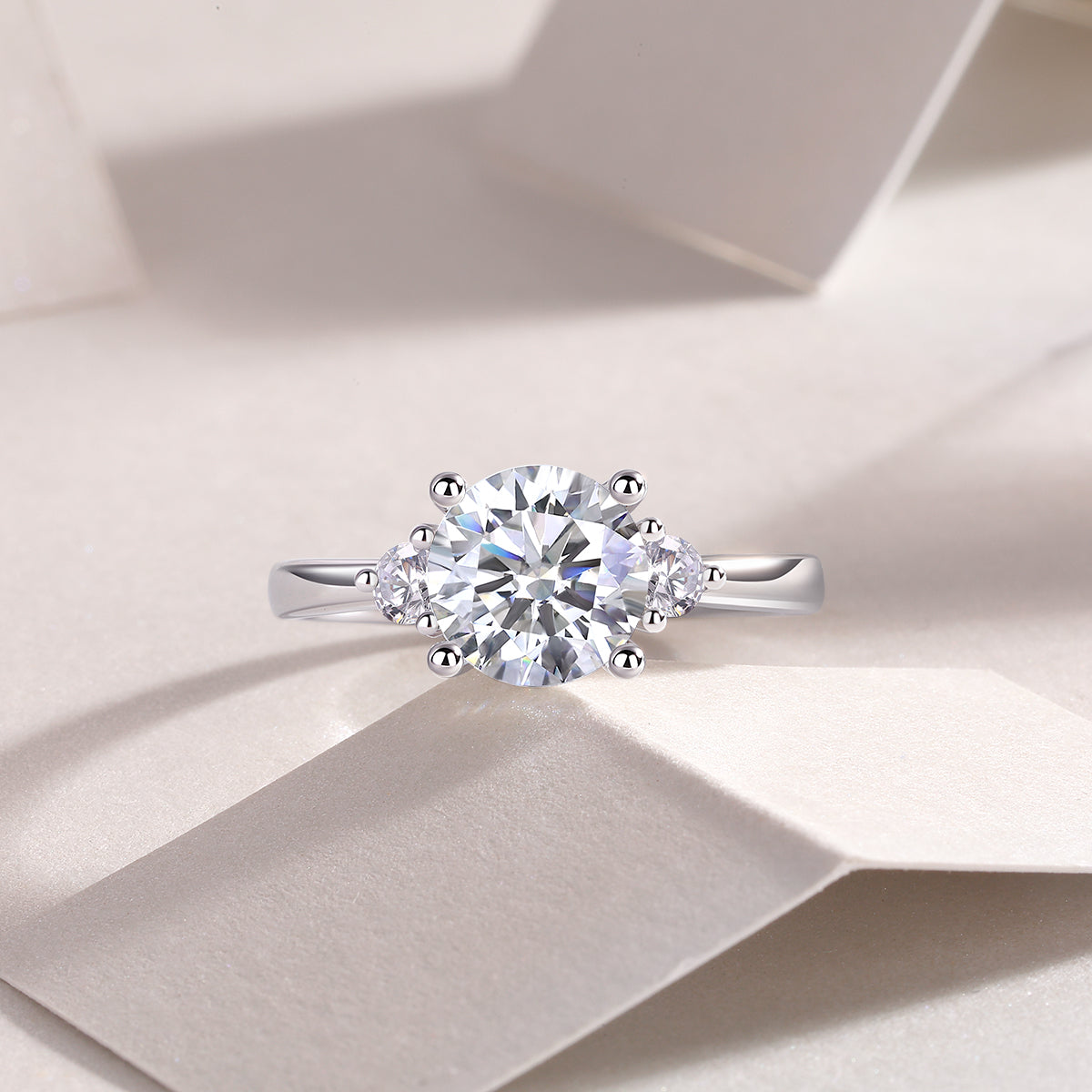 CARISSIE moissanite ring on textured surface, top-down shot emphasizing the sparkle of the stones against soft shadows