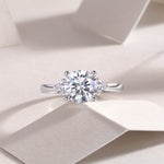 CARISSIE moissanite ring on textured surface, top-down shot emphasizing the sparkle of the stones against soft shadows